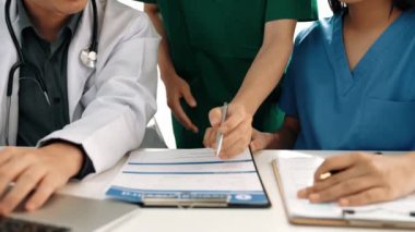 Hastane masasında birlikte çalışan ve tıbbi tedavi planlayan çeşitli profesyonel sağlık görevlileri. Takım çalışması başarılı hastalıklara ve hastalıklara yol açar. Ağır çekim. Katı.