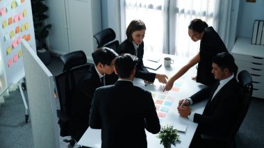 Akıllı yönetici finansal grafiğinin üst görüntüsünden çeşitli takımlara geçerken, bir grup çok kültürlü iş adamı toplantıda hisse yatırım grafiği kullanarak pazarlama stratejisi planlıyorlar. Müdürlük.