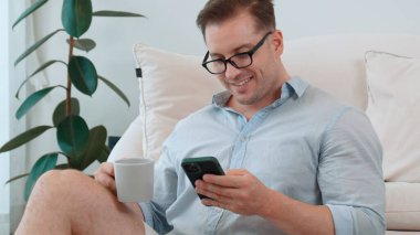 Orta yaşlı bir adam, iş için telefon arama verilerini kullanarak, çocukları iyi bir yetişkin ya da eğlence olsun diye odada kahve fincanıyla koltukta oturur. İşadamı teknolojiyi kolaylık için kullanır. Uyumsuzluk.