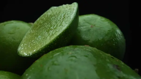 Stock image Slices of lime are meticulously arranged in a pile, set against a black background. Each lime slice is captured in stunning detail, its vibrant green hue and enticing texture. Close up. Comestible.