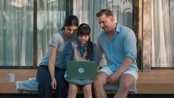 stock image Father, mother and daughter focus laptop at terrace with garden view outside house. Parent use outdoor activity to communicate young generation about environment care cross generation gap. Divergence.