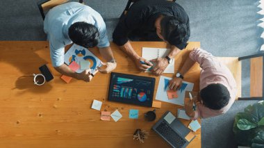 Yönetici, toplantı odasındaki meslektaşlarına mali grafiği açıklar. Farklı pazarlama ekibinin tabletle masada otururken fikir ve planlama stratejisini en üst düzeyde paylaşması. Cemaat.