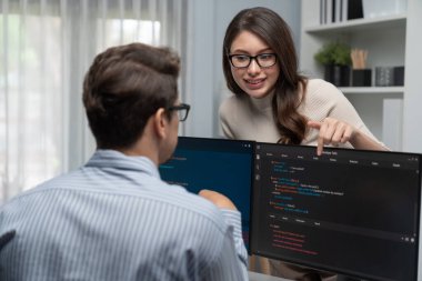 Masada çalışan erkek programcının karşısında duran kadın meslektaşım iki bilgisayar ekranında kodlama web sitesi yazılım sistemi projesini tartışmak için tam yığın veri dizaynı ile karşılaştırıyor. Varsayım.