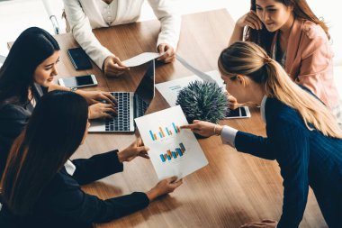 Modern işyeri ofisindeki diğer iş kadınlarıyla grup toplantısındaki iş kadını masada dizüstü bilgisayar ve belgelerle konuşuyor. Kurumsal iş dünyası konsepti. uds