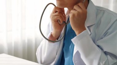 Hasta klinikte ya da hastane ofisinde doktor randevusuna gidiyor. Hastaların nabzını steteskopla kontrol edip risk faktörünü belirleyen doktor semptomları inceliyor. Panorama. Katı.