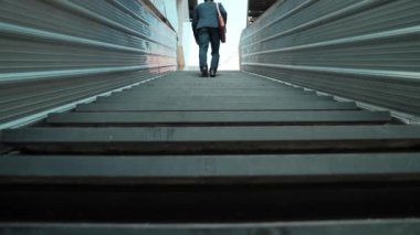 Merdivenlerden çıkan başarılı iş adamının bacağına yakın plan. Müdürün iş yerini değiştirmesi, yeni bir şey keşfetmesi, gelişmesi, terfi etmesi ya da gün ışığına çıkması. Yükseliyor. Bacağa odaklan. Sevinçli..