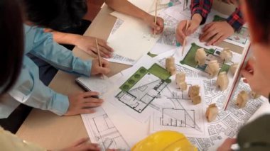 Mimari belge, ölçüm aracı ve ahşap blokların modern ofiste etrafa saçıldığı bir masa üzerinde yapı inşaatı ile ilgili mimar ve güvenlik mühendisi tartışması. Tanımlama.