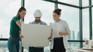 Proje planına bakarken tasarımla ilgili düşünen, paylaşan, beyin fırtınası yapan profesyonel mimar mühendis takımı. Yönetici planı dinlerken genç mimar plan yapıyor. İzleme