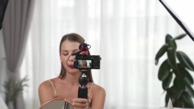 Sosyal medya için güzellik ve kozmetik video içeriği hazırlayan genç bir kadın. Güzellik blogcusu kameraya gülümserken seyircilere ve takipçilere güzellik bakımını gösteriyor. Düzenle