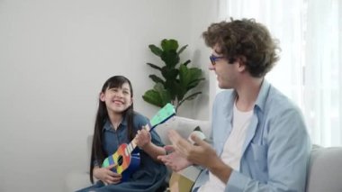 Mutlu bir babanın, ukulele çalan ve şarkı söyleyen akıllı kızına bakışının arkası. Mutlu baba motive oldu ve Amerikalı liseli kızı gitar çalmaktan zevk almaya teşvik etti. Aile eğlencesi. Pedagoji.