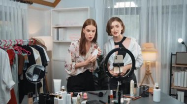 İki kadın nüfuzlu partner sosyal medya veya blog için canlı yayın yapan video klip inceleme derisi çekiyorlar. Kozmetik stüdyosu ışıklandırması olan genç bir kız pazarlama oturumu çevrimiçi yayın yapıyor.