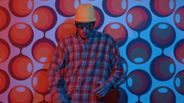 Profesyonel break dansçı, parti sahnesinde balon arka planlı gözlük takıyor. Havalı giyinen yetenekli bir sanatçı enerjik hareketler ve ayak sesleri göstererek müziğe yöneliyor. Mutluluk.