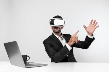 Bilgisayarla masada otururken ve VR gözlüğü takarken veri analizine bakan yetenekli bir iş adamı. Proje yöneticisi sanal gerçeklik sistemini kullanarak ya da metaevrende bağlantı kurarak çalışıyor. Sapma.