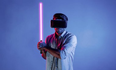 Kafkasyalı bir adam VR cam takıyor ve hareket eden el kol kılıcını tutuyor. Oyuncu, gelecekteki sanal gerçeklik kulaklığını ya da gelecekteki yenilikleri kullanarak meta dünyaya giriyor ya da aksiyon oyunu oynuyor. Sapma.