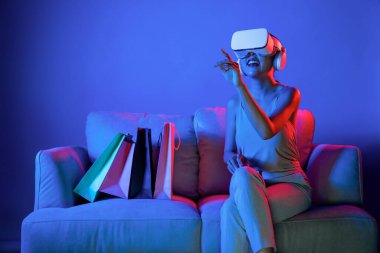 Akıllı kadınlar koltukta çantaların yanında otururlar. Meta-evrene bağlı VR kulaklık takarlar. Gelecekteki siber uzay topluluğu teknolojisi. Zarif bir kadın, meta dünyadaki çevrimiçi mağazalardan alışveriş yapmaktan hoşlanıyor. Halüsinasyon.