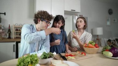 Çekici beyaz anne ve baba Asyalı kızıyla taze yemek pişirmek için birlikte vakit geçiriyorlar. Annem ve babam mutfakta salata yapmak ve sebze yemek için taze sebze hazırlıyorlar. Pedagoji.