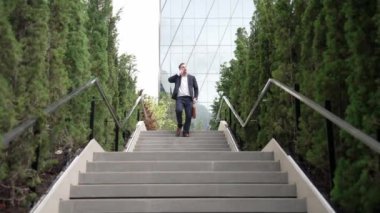 Mutlu iş adamı merdivenlerden inip akıllı telefon kullanarak müdürü arıyor. Yöneticinin pazarlama ekibinden bahsetmesi ve merdivenlerden inerken telefonla finansal strateji planlaması. Urbane.