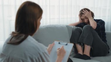 Psikologla ruh sağlığı terapisi gören üzgün travma sonrası stres bozukluğu olan bir kadın. Yaşam sonrası depresyon veya keder. Hayal kırıklığına uğramış genç bir kadın klinikteki duygular hakkında prim psikoloğuyla konuşuyor.
