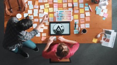 Renk paletinden renk seçmek için birlikte çalışan iş adamlarının en üst görüşü. Proje yöneticisi, logo grafiklerine bakarken pazarlama ekibine tablet kullanarak fikir sunuyor. Sempozyum.