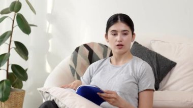 Kanepede oturan bir kadın ders kitabı okuyarak sosyal ve mesleki teknoloji bilgisini artırır ya da akıllı bir anne olmak için çocuk yetiştirir. Hayat boyu öğrenme konsepti. Uyumsuzluk.