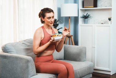 Spor giyimli sağlıklı ve vejetaryen bir kadın bir kase meyve ve sebzeyle. Sağlıklı beslenme ve spor için vejetaryen yaşam tarzı ev konseptinde vücut fiziği.