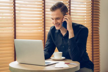 Mutlu iş adamı ya da satıcı online iş yapıyor, uzaktan kumandayla çalışıyor ve evdeki satışlar için telefon görüşmesi yapıyor. Telesyaller ve iletişim ile modern iş. Açılıyor