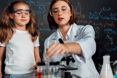 Laboratuvarda çalışan öğretmen, güvenlik gözlüğü takıyor, STEM sınıfında kimya bilimi üzerine deney yapıyor. Öğrenci komedisi tüpte sıvı deneyi yapar. Etkinlik.