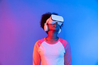 Profil, VR gözlük takan genç ve güzel Afrikalıların mavi ve pembe neon ışıklı arkaplanda izole olduğunu düşünüyor. Teknoloji ve dijital yenilik 3 boyutlu hologram gramında. Entrika.