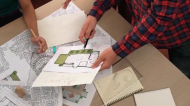 Mimari döküman, ölçüm araçları ve ahşap blokların modern ofiste etrafa saçıldığı masa üzerine planlar yapma konusunda akıllı mimar ve güvenlik mühendisi tartışması. - Yakın çekim. Tanımlama.