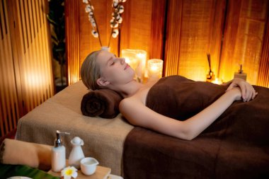 Beyaz kadın müşteri stres önleyici spa masajının keyfini çıkarıyor ve lüks otel ya da otelde sıcak mum ışığında güzellik teniyle eğleniyor. Sessiz.