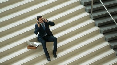 Merdivenlerde otururken kulaklıktan müzik dinleyen zeki bir iş adamı. Mutlu menajer dans ederken ya da müzikle uğraşırken gülümsüyor. Yatırımcı iyi haberler alıyor, terfi alıyor. Sevinçli..