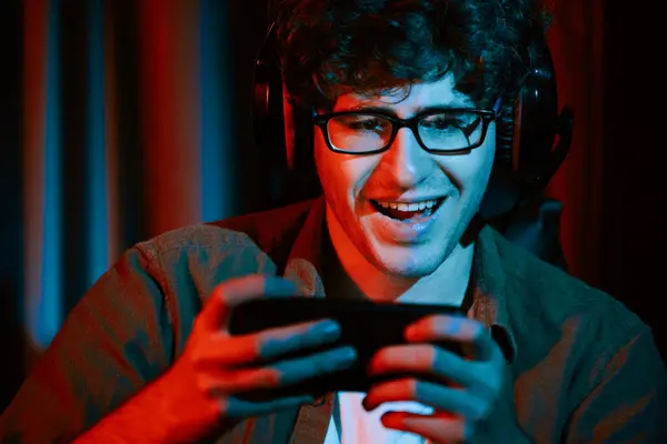 stock image Stressful young gaming streamer team playing with Esport online on smartphone fighting harder game level with surprise face and shame for winning at neon light room. Practising strategy plan. Gusher.