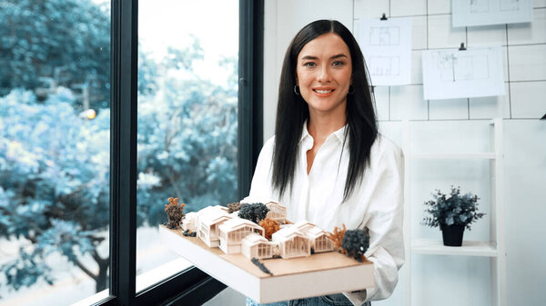 Крупный план квалифицированного молодого красивого кавказского архитектора лифта дом модели левой и правой стороны, чтобы проверить и сосредоточиться на проверке ошибок точки в современном офисе с чертежом. Непорочный.