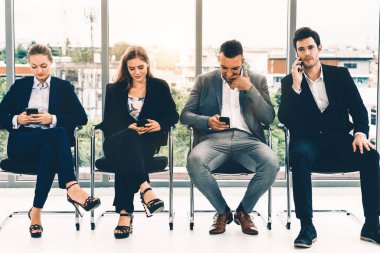 İş kadınları ve işadamları iş görüşmesi için koltuklarda beklerken cep telefonu kullanıyorlar. Şirket işi ve insan kaynakları kavramı. uds