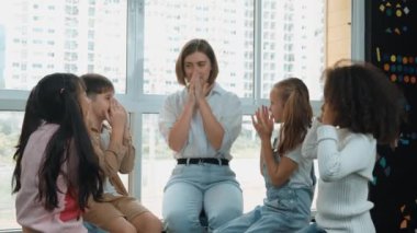 Farklı öğrencilerle çevrili yerde birlikte otururken, zeki beyaz bir öğretmen ders veriyor. Çok kültürlü bir öğrenciyle oynayan profesyonel bir eğitmen. Yaratıcı eğitim konsepti. Etkinlik.