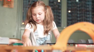 Yaratıcılığı geliştirmek ve geliştirmek için oyuncak oynayan çok kültürlü bir kız. İlkokuldaki oyun odasında araba mankeni tutan çeşitli öğrenciler ara verdiklerinde oturuyorlar. Yaratıcı aktivite konsepti. Etkinlik.