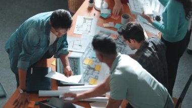 İnşaat inşaatı sırasında akıllı inşaat mühendisi proje planının en üst görünümü. Mimarla iç mimar birlikte çalışırken dizüstü bilgisayar kullanarak planı kontrol ediyorlar. Sempozyum.