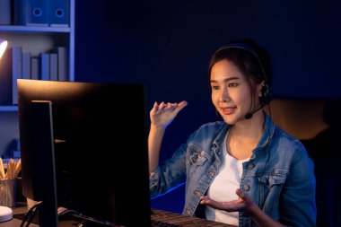 Sunucu kanalı Asyalı etkileyicisi canlı yayında konuşuyor. Sosyal medyada kulaklık takıyor, bilgisayar kaydı yapıyor, dinleyicileri selamlıyor ve Neon Modern Stüdyoları 'nda online olarak koçluk yapıyor. Taktik.