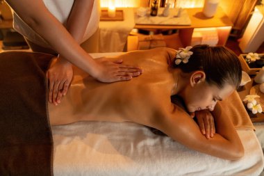 Beyaz kadın müşteri stres önleyici spa masajının keyfini çıkarıyor ve lüks otel ya da otelde sıcak mum ışığında güzellik teniyle eğleniyor. Sessiz.