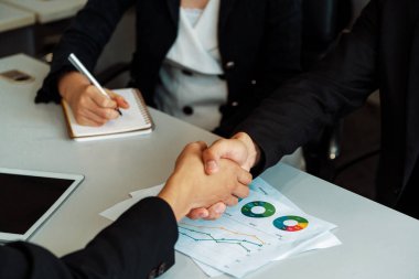 İş adamları konsepti kabul ediyor. İş adamı ve Asyalı iş kadını ofiste el sıkışırlar. uds