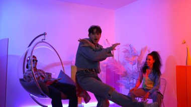 Çok kültürlü bir arkadaş kürsüde otururken Asyalı yetenekli bir dansçı modern müziğe geçiyor. Profesyonel dansçı, hipster takımı tezahürat yaparken ve desteklerken enerjik adımlar atıyor. Mutluluk.