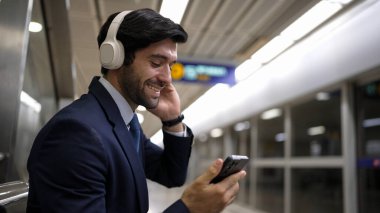 Tren istasyonunda geçmişi bulanık bir şekilde beklerken kulaklıkla müzik dinleyen zeki bir iş adamı. Yetenekli proje yöneticisi cep telefonu tutarken dinlenme sesi dinlemeyi sever. Sevinçli..