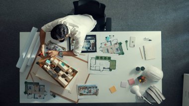 İş adamının tablet ev tasarımını kullanırken plan ve ekipmanların etrafa saçıldığı toplantı masasında oturduğu en iyi manzara. Bina planında çalışan inşaat mühendisinin hava görüntüsü. Hizalama.