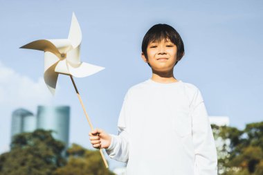 Küçük Asyalı çocuk rüzgar değirmeni ya da rüzgar türbini modelini tutarak eko temiz ve yenilenebilir enerji teknolojisini gelecek nesil ve sürdürülebilir Dünya için kullanmaya teşvik ediyor. Döngü