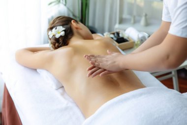 Masör elleri kadının sırtına aroma yağı döküyor. Masözler lüks otellerdeki kaplıca salonundaki müşteriler için yağ masajı prosedürü hazırlıyorlar. Aroma yağı vücut masajı konsepti. Sessiz.