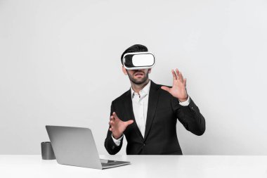 Bilgisayarla masada otururken ve VR gözlüğü takarken veri analizine bakan yetenekli bir iş adamı. Proje yöneticisi sanal gerçeklik sistemini kullanarak ya da metaevrende bağlantı kurarak çalışıyor. Sapma.