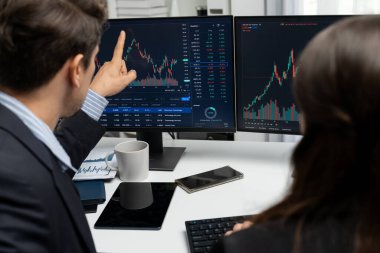 Dinamik borsada döviz kuru yatırımını tartışan iki ticaret simsarı iki bilgisayar ekranında gerçek zamanlı risk grafiği ya da modern ofisteki kar noktasını karşılaştırıyor. Varsayım.