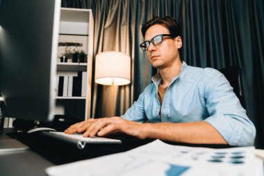 Akıllı iş adamı iş paragrafı dinamik pazarlama analizi planını analiz ediyor. Kağıt kağıtları ve bilgisayar monitörü raporlarını gece evdeki belge verileriyle karşılaştırmak için hazırlıyor. Bireysel.