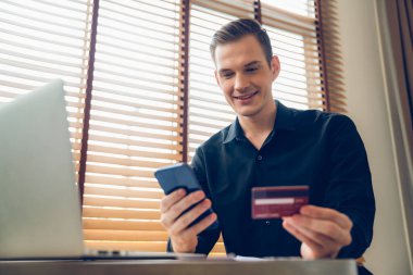 Genç adam internet bankacılığı için kredi kartlı dizüstü bilgisayar kullanıyor. İnternet üzerinden alışveriş yapıyor. Banka kartıyla modern ve kullanışlı online satın alma. Açılıyor