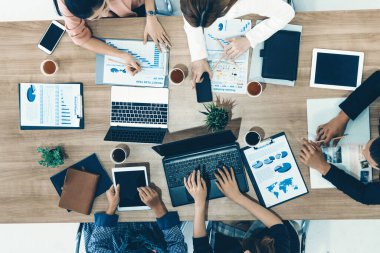 Modern ofisteki iş adamları ve iş kadınlarıyla grup toplantısındaki iş adamlarının en üst düzey görüşü, masada dizüstü bilgisayar, kahve ve belge ile. Kurumsal şirketler uds